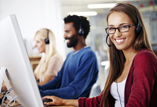 woman smiling at computer wearing headset